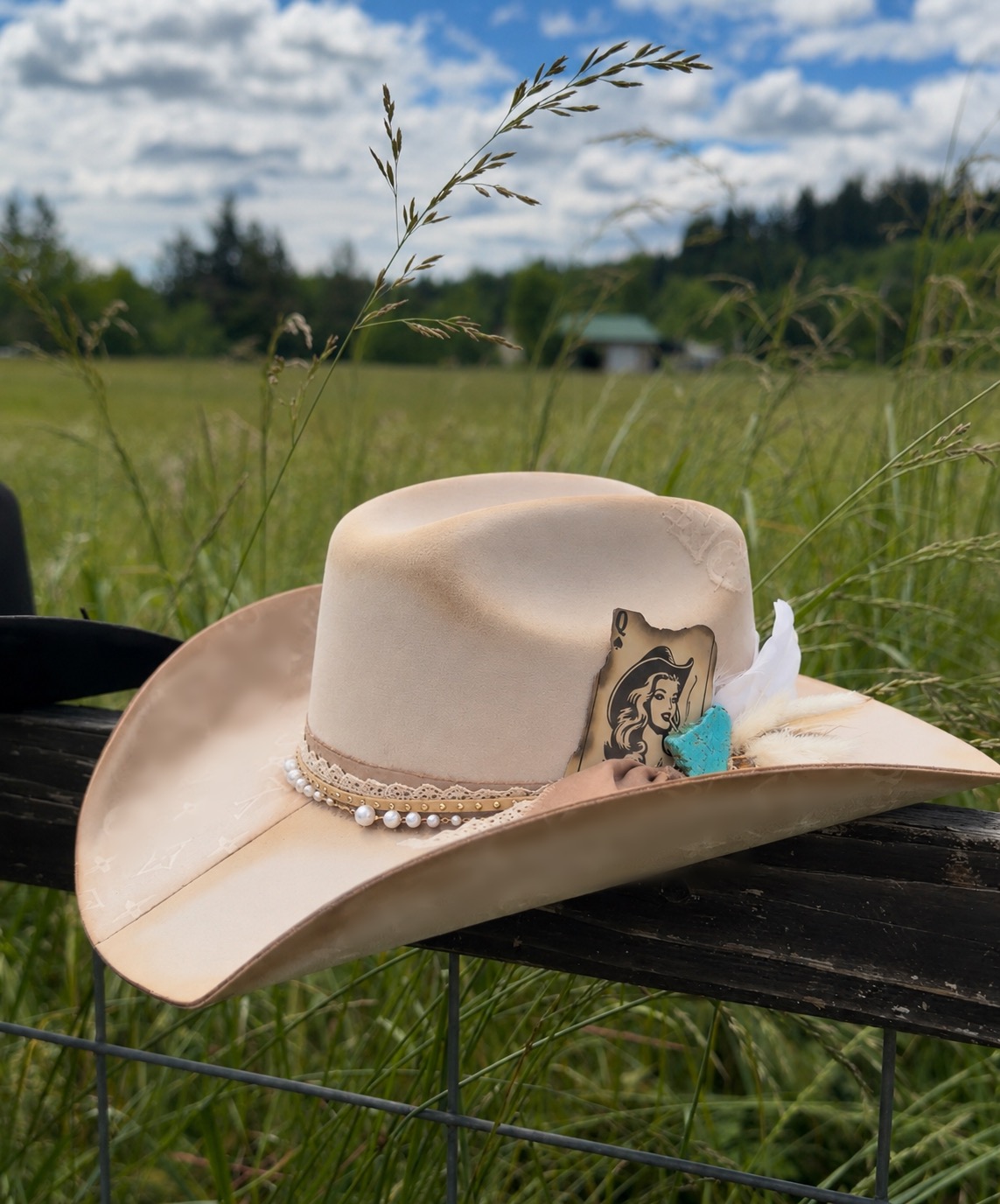 West n' Luxe cream cowboy hat with turquoise, pearls, and feathers in an Oregon field